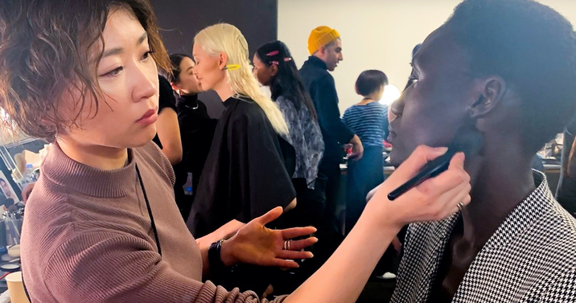 The lead image shows a model getting making done at NYFW.