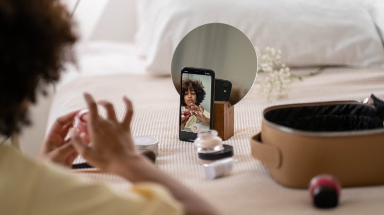 Photograph of woman recording herself putting on makeup.