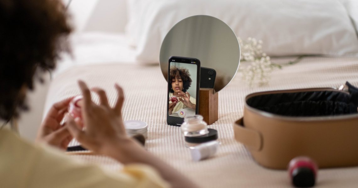 Photograph of woman recording herself putting on makeup.