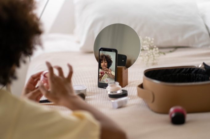 Photograph of woman recording herself putting on makeup.